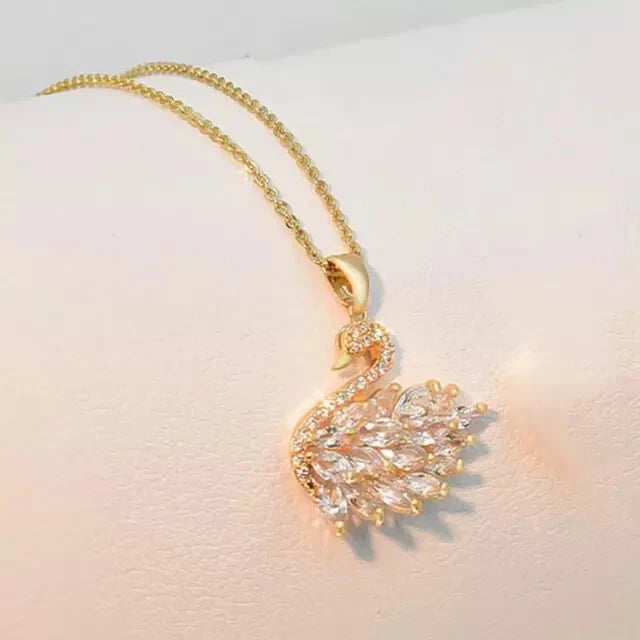 Gold swan-shaped necklace with clear stones on a light background