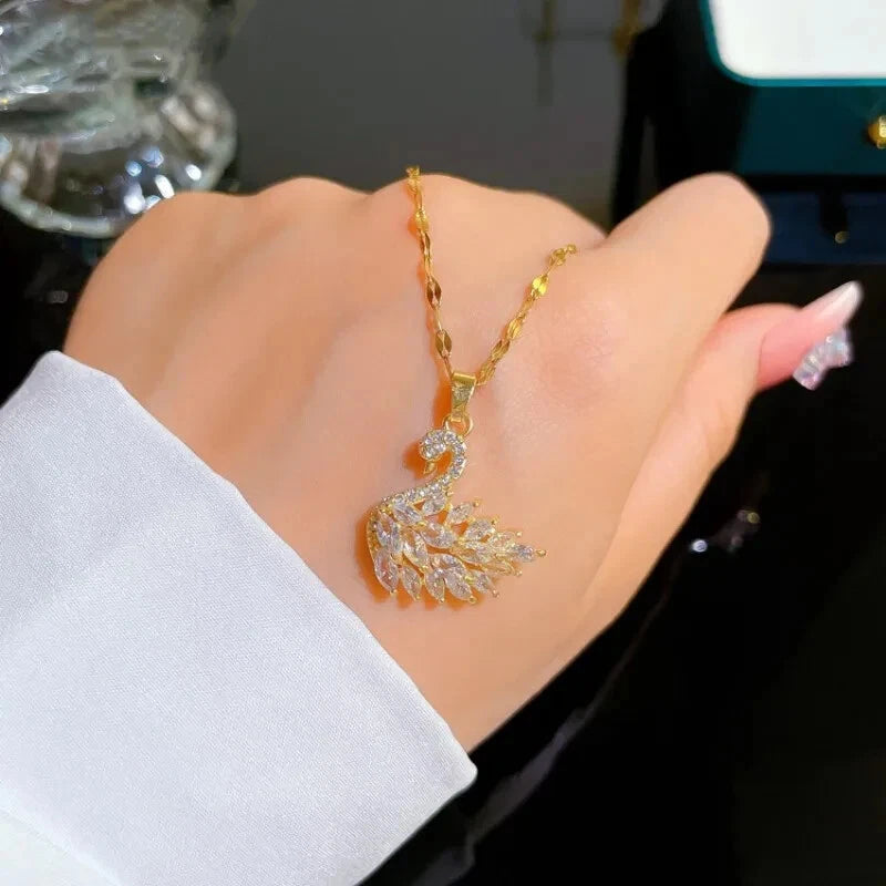 Gold necklace with a leaf-shaped pendant on a hand against a dark background