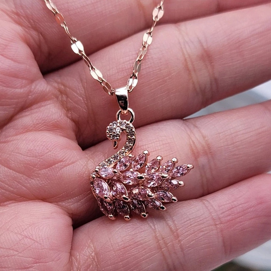 Rose gold necklace with a pink gemstone pendant held in a hand.
