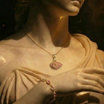 Statue wearing a gold necklace and bracelet with pink stones