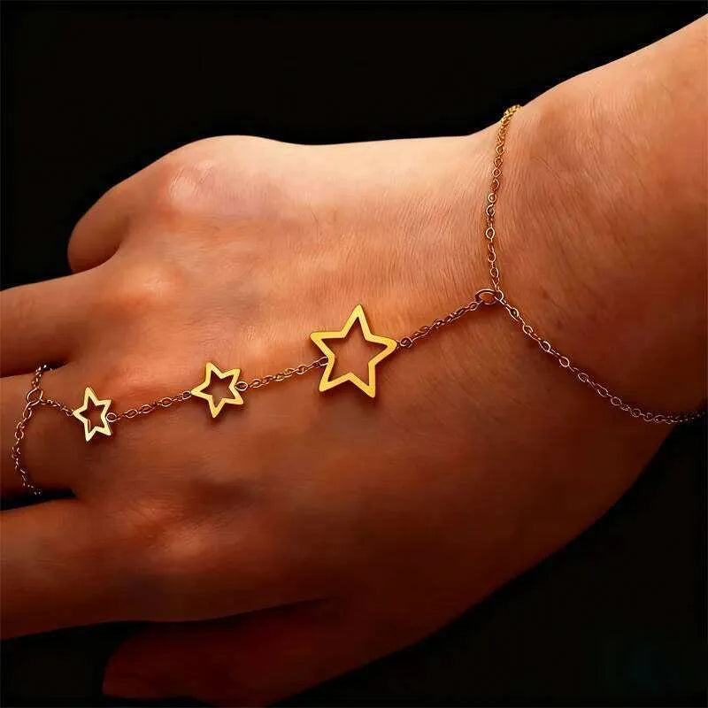 Gold star bracelet on a wrist against a black background