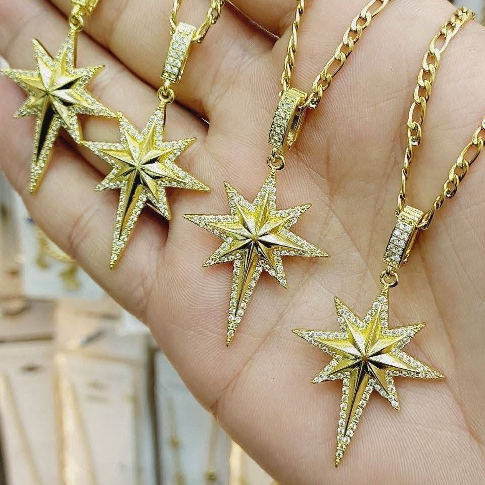 Gold star-shaped pendants on a hand with a blurred background