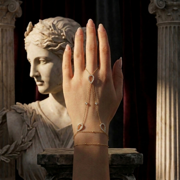 Gold bracelet with gemstones on a hand against a neutral background