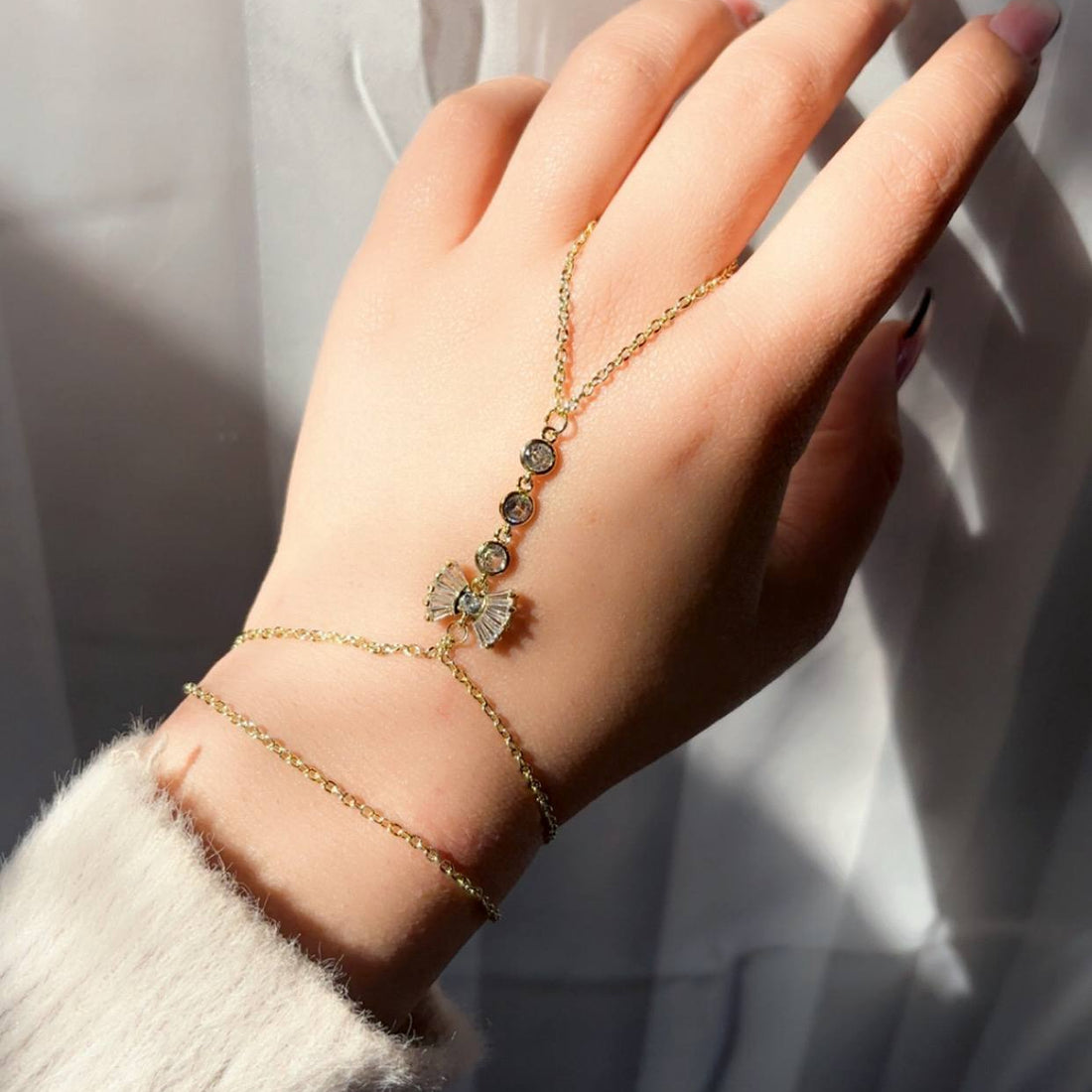 Hand wearing a gold bracelet with a statue in the background