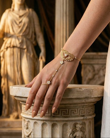Hand wearing a gold bracelet with a statue in the background