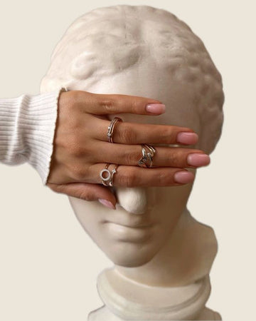 Hand wearing multiple rings on a marble bust