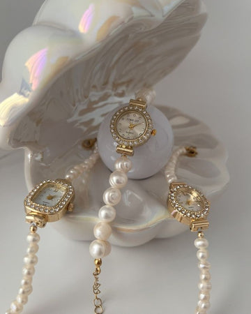 Pearl necklace with gold watch and bracelet on a shell