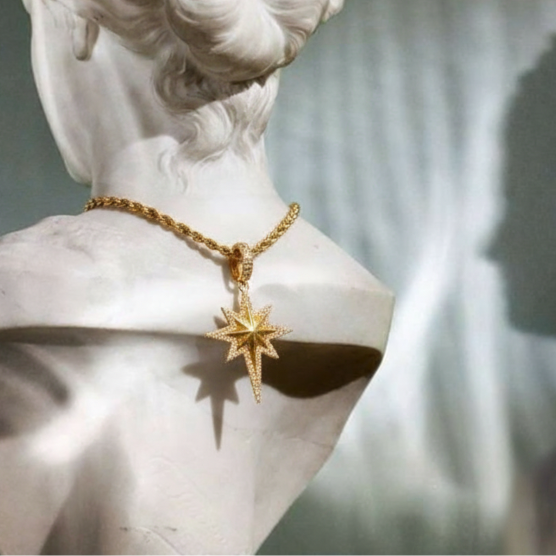 Gold necklace with a star pendant on a marble bust